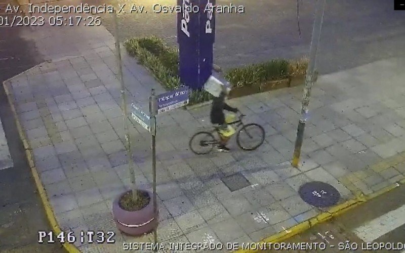 No vídeo, é possível ver o homem de bicicleta e carregando o micro-ondas no ombro