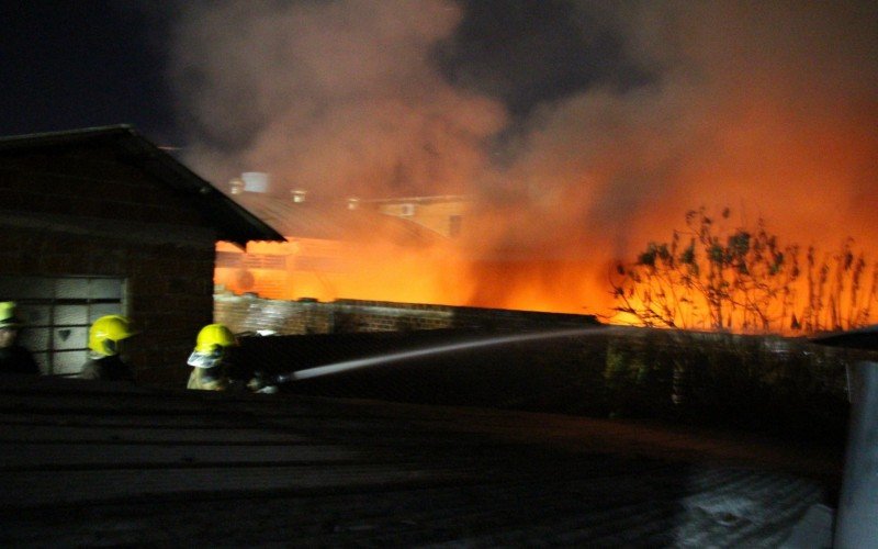 Bombeiros combatendo incÃªndio para evitar chegada das chamas Ã s casas situadas na Rua ChapecÃ³