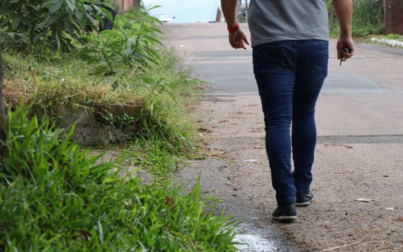 Pedestre caminha sobre o asfalto no bairro Canudos porque passeio está intransitável | Jornal NH