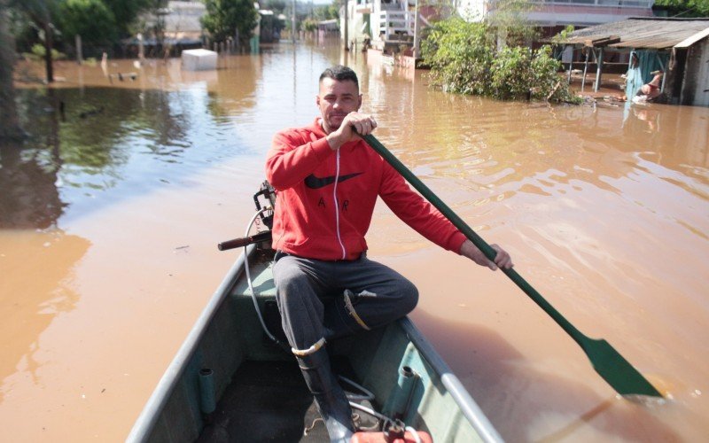 De barco, Marco Aurélio Horn Filho, 43 anos, pedreiro, ajuda vizinhos que permaneceram em casa