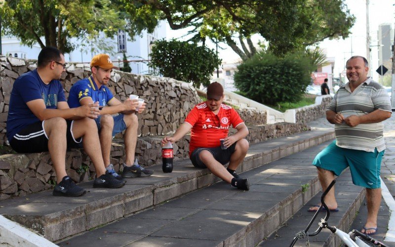 Os amigos Adriano Nunes (direita), 53, Deivid Lemos (de vermelho), 28, e Leonardo Souza (de bonÃ©), 26, aproveitaram a tarde de calor para tomar um refrigerante na praÃ§a de SÃ£o SebastiÃ£o do CaÃ­