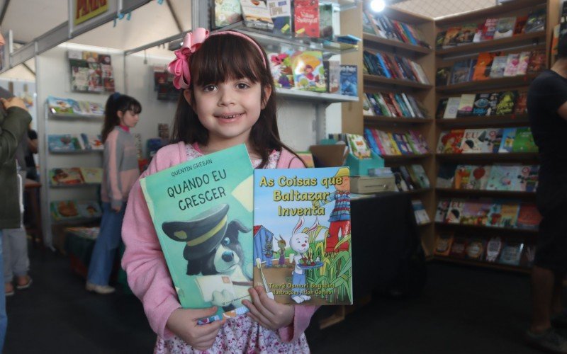 Raíssa, 6 anos, mostra os livros que comprou na feira