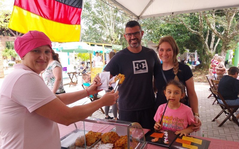 Depois de Manuela escolher seus livros nos estandes, a famÃ­lia comprou bolinhos de batata com liguiÃ§a de  Roselei
