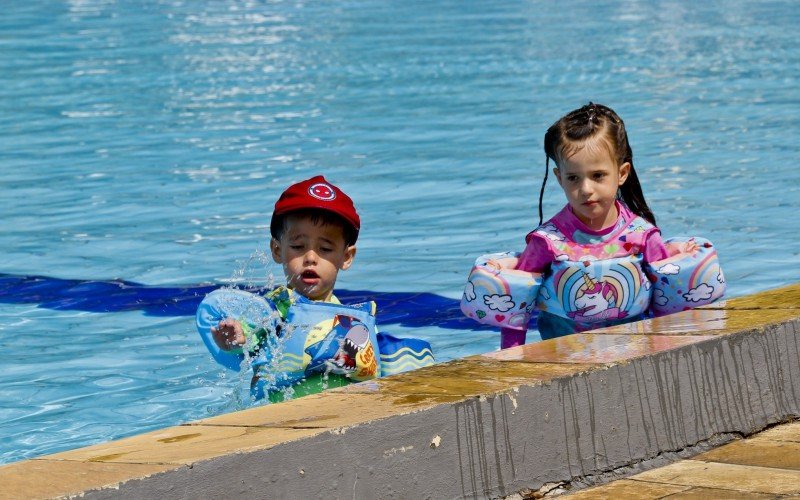 Irmãos gêmeos Giovana e Gabriel curtem uma piscina