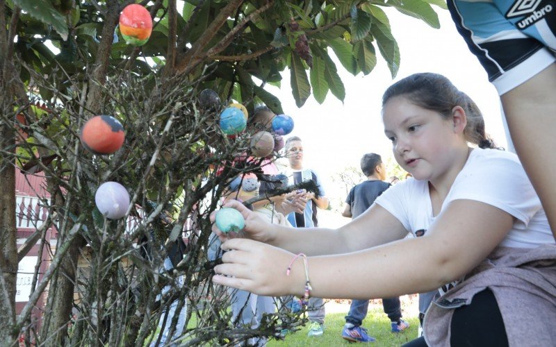 Crianças enfeitam árvores na Vila de Páscoa 