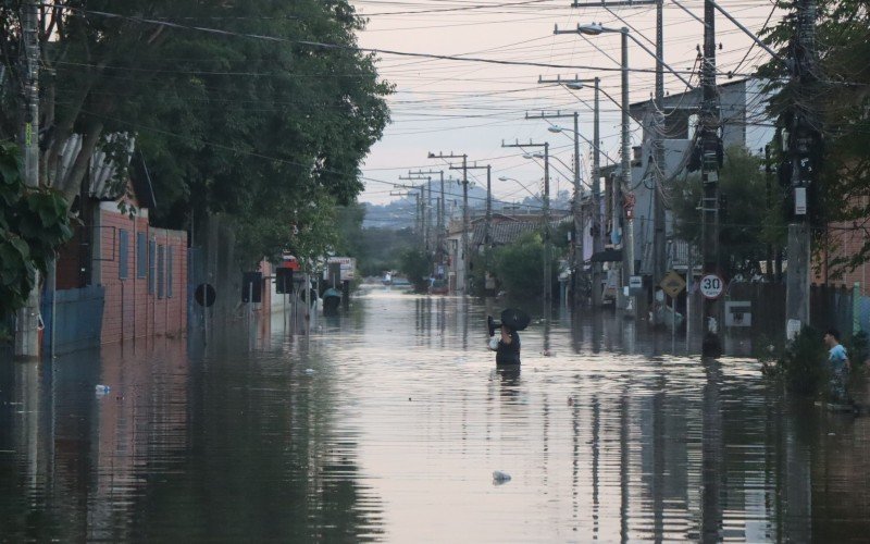 Com água pela cintura, moradores buscam salvar pertences