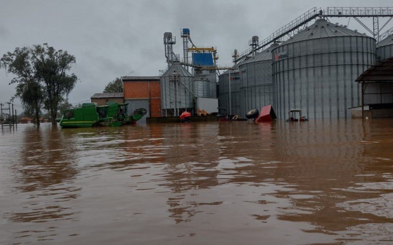 Fazenda produtora de arroz inundada. Silos com arroz já colhido dentro e maquinários na água