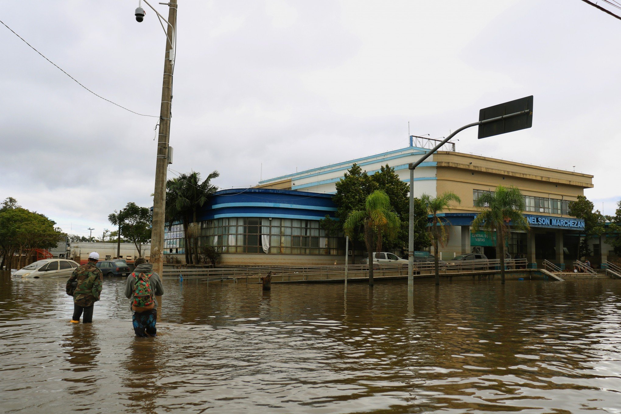 Com o recuo das águas, moradores caminham em frente ao Hospital de Pronto Socorro