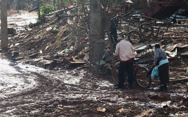 Moradores caminham sobre área que estava alagada