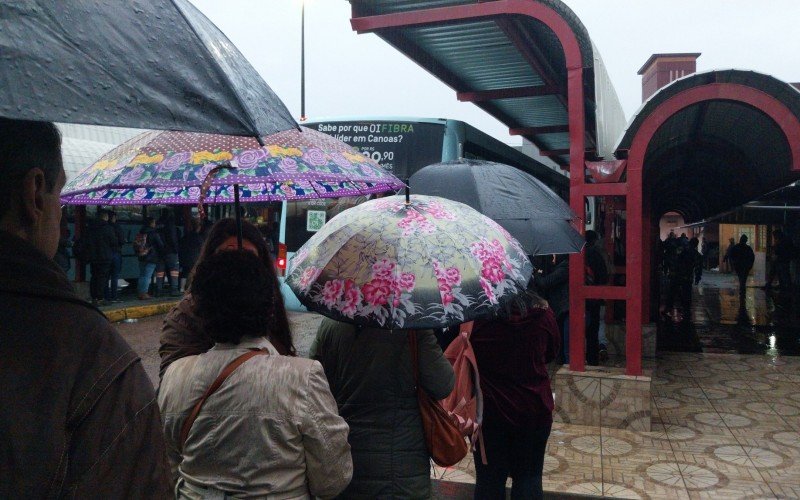 Usuários aguardam na chuva para embarcar em ônibus da Transcal