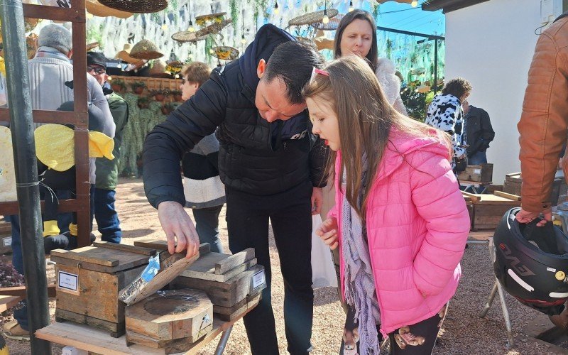 Pai e filha conferem de perto caixa de abelha exposta na Feira do Mel, Rosca e Nata