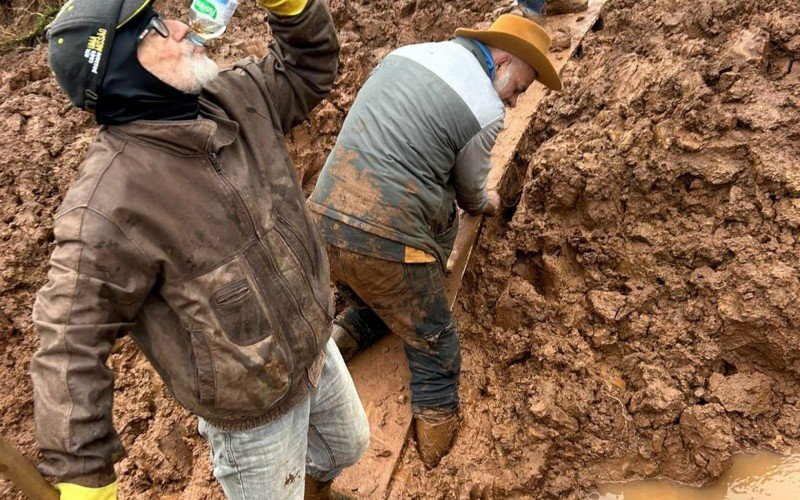 Moradores e voluntários constroem caminho sobre a lama para acessar local