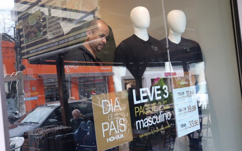 Gerente de uma loja na Rua Independência, Jonatan Trindade arruma a vitrine que anuncia promoção especial para o Dia dos Pais