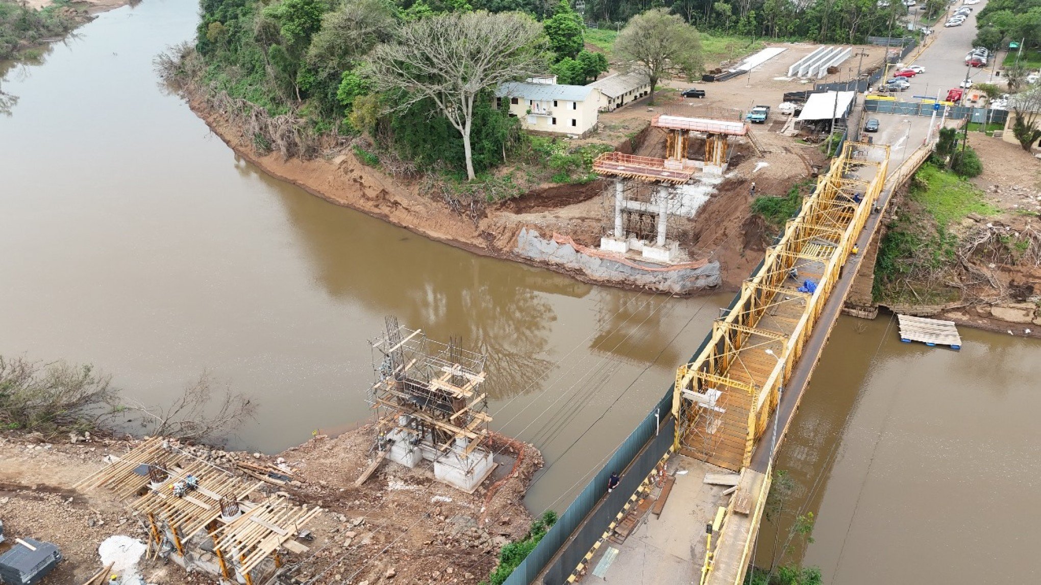 Vista aérea da centenária Ponte de Ferro sobre o Rio Caí (à direita), na cidade de Feliz, ao lado dos pilares de concreto da estrutura que está em construção | abc+