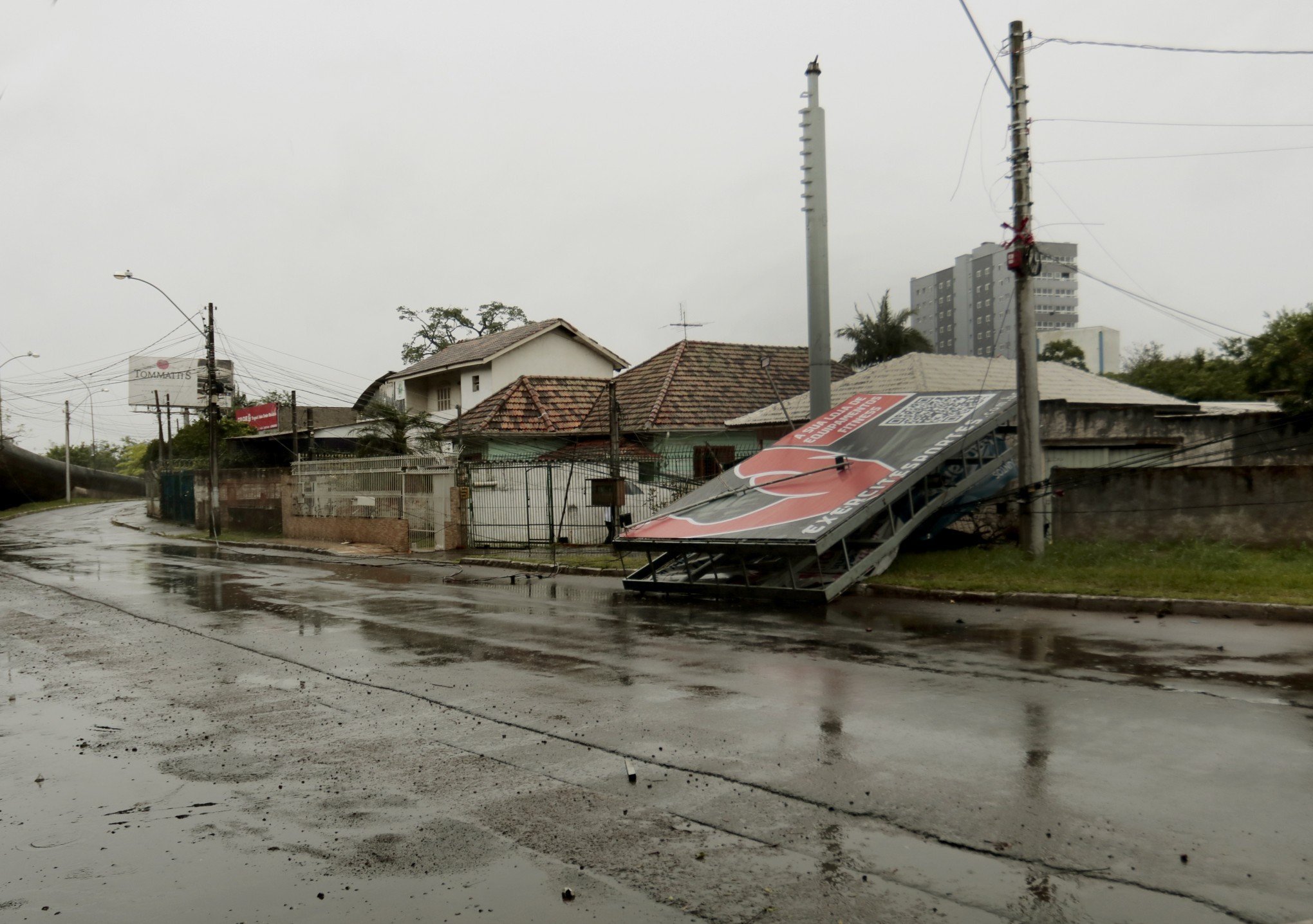 Placa de publicidade cai no terreno de duas residências após ventania no Centro