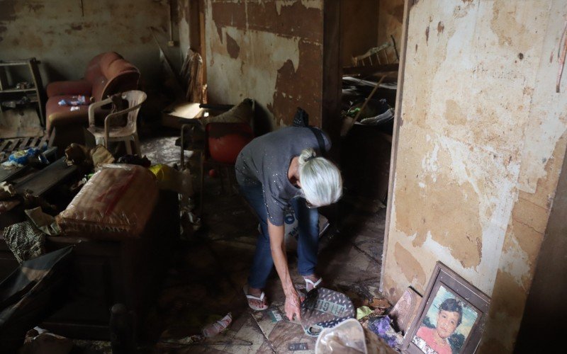 Geni ficou cabisbaixa ao encontrar pertences atingidos pela inundação em sua casa