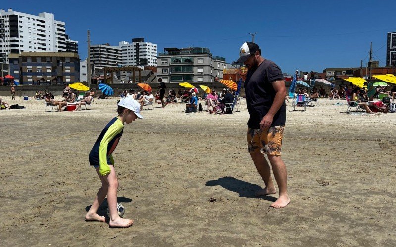 Pai e filho aproveitam dia bonito para jogar bola na faixa de areia 