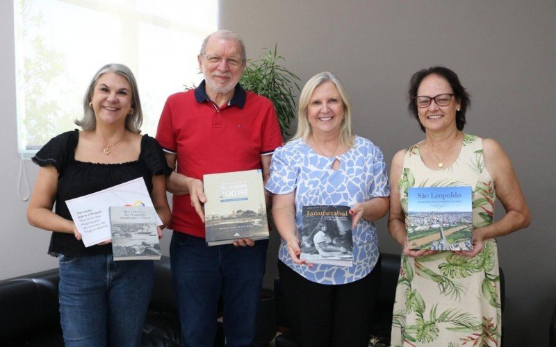 Município de Sapiranga já recebeu exemplares dos livros; na foto, Erny, acompanhado da historiadora Doris Fernandes (D), entregando os exemplares para a prefeita, Carina Nath (de azul, ao lado de Erny), e a secretária de Educação, Cláudia Kichler