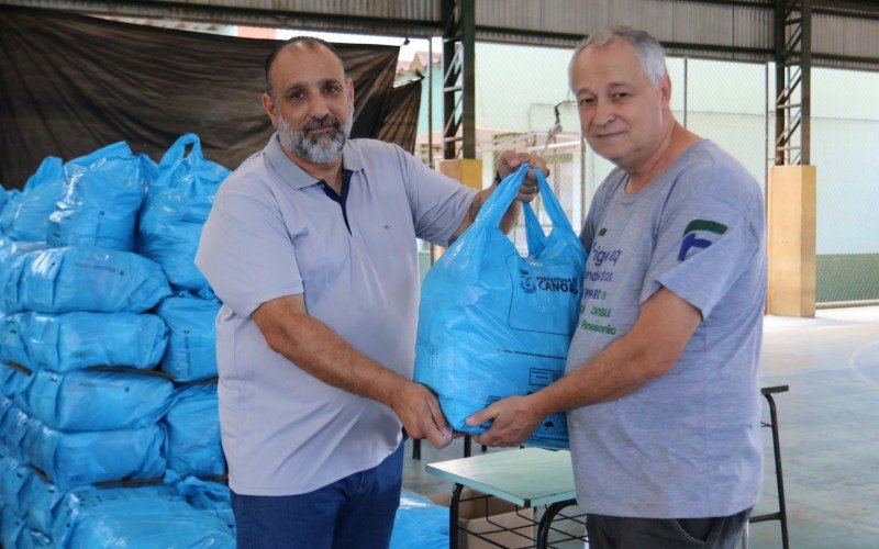 Alexandre Sironi (à direita) retira cesta básica na Emef Nelson Paim Terra