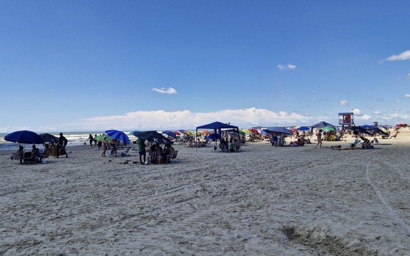 Mesmo com água mais escura, banhistas seguem aos montes na praia
