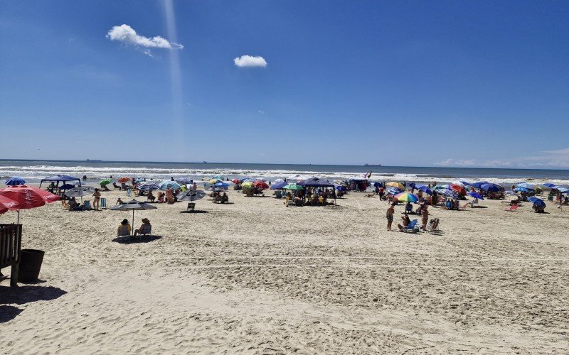 Mesmo com água mais escura, banhistas seguem aos montes na praia