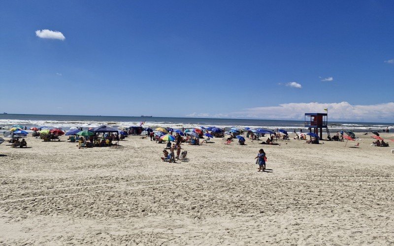 Mesmo com água mais escura, banhistas seguem aos montes na praia