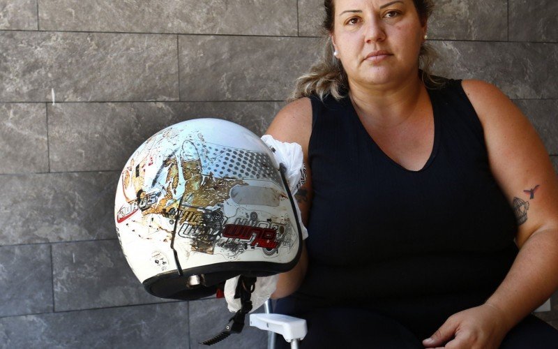 Franciele da Silva segura o capacete usado pelo filho no momento em que acabou atingindo por um carro na última sexta-feira (31)