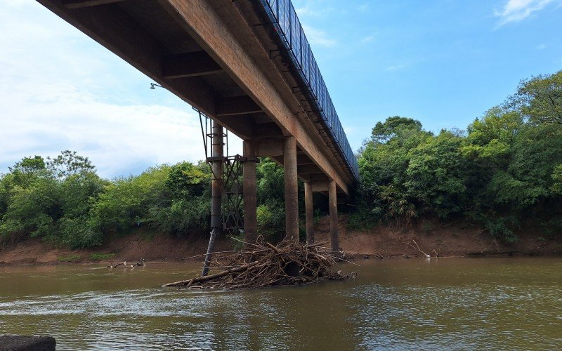 Com o nível baixo, o fundo do rio está exposto, revelando acúmulo de sujeira e troncos presos nos pilares da ponte na Barrinha, em Campo Bom