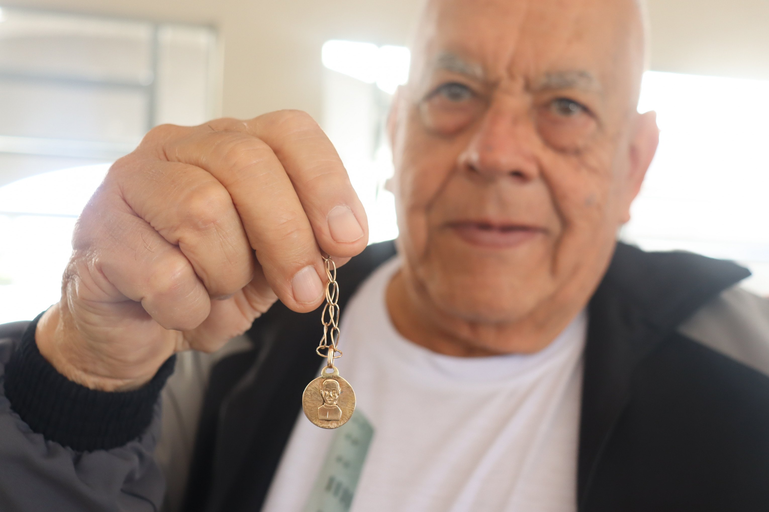 Devoto de Padre Reus, Albino mostra medalhinha com imagem do pároco que ganhou há 50 anos