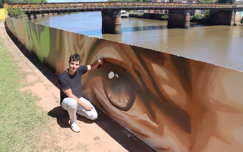 Artista Feu Cardoso mostra detalhes dos desenhos feitos no muro do dique da Praça do Imigrante