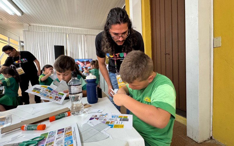 Autor do projeto, Abimael Esteva, explica às crianças como montar a minibiblioteca