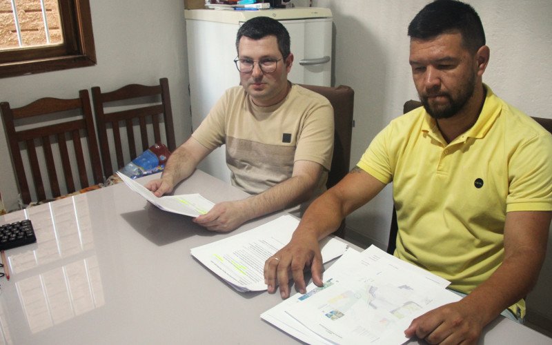 Anderson e Jonathan guardam documentos que falam sobre ações e enchentes na Vila Integração
