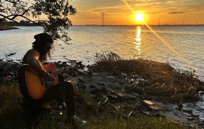 Entre o pôr do sol e o violão, artista de Tramandaí transforma a cidade em música