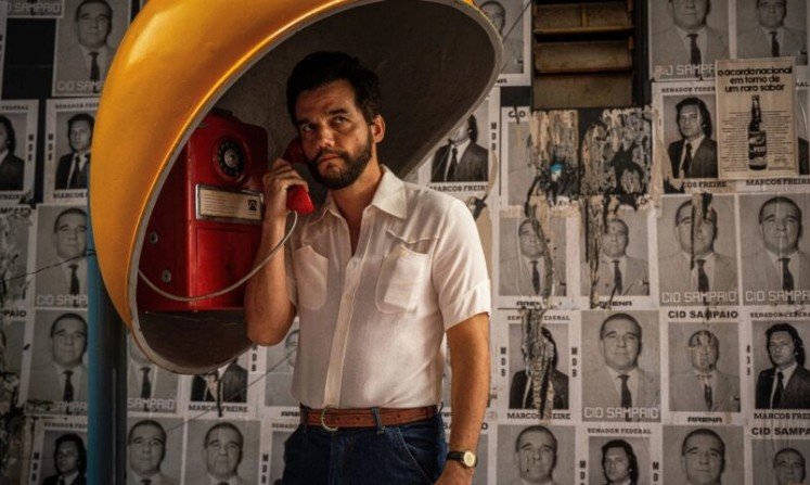 Wagner Moura em um orelhão, imagem que correu o mundo devido à divulgação do sucesso "O Agente Secreto" no exterior | abc+