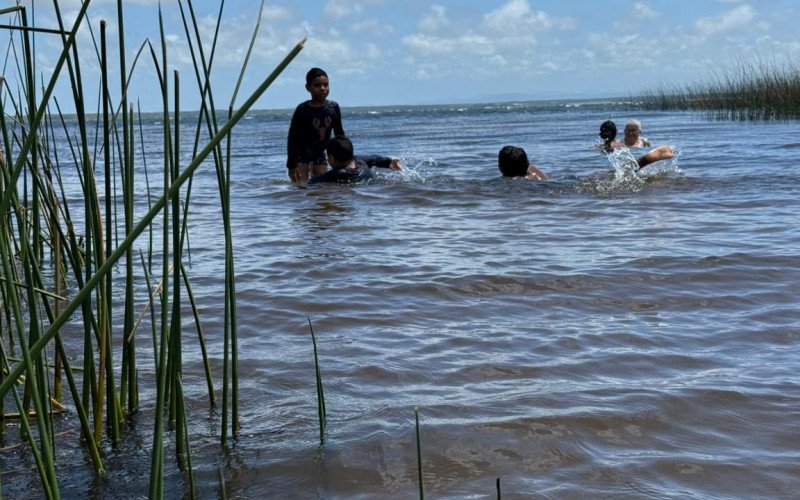Crianças aproveitam o dia quente para se banhar no lago