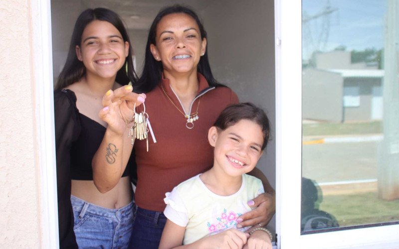 Greici Kelli (&agrave; direita, de laranja) mora com as filhas Evyllyn (de preto) e Isabelly (de branco) e conquistou sua primeira casa pr&oacute;pria