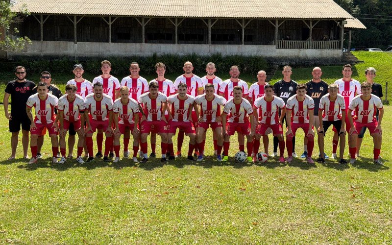 Com o galpão ao fundo, elenco atual do Grêmio Atlético Rio Branco posa com o fardamento de 2026 | abc+