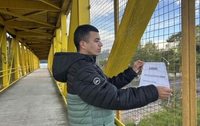 Usuários colocam cartazes para alertar sobre risco de assaltos em passarela da BR-116