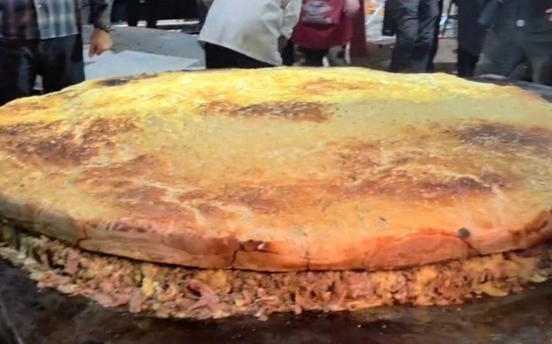 Maior hambúrguer do País e chef Edi Dagrê erguendo o troféu da maior linguiça: recordes batidos em Esteio 