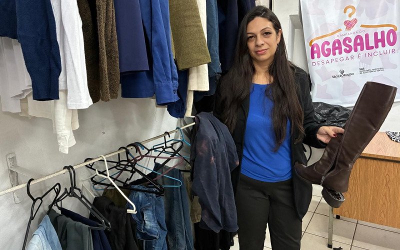 Coordenadora do Banco do Agasalho, Francine Lucchese, mostra peças de descarte que chegam via doação, como camisa manchada e bota com solado descolado