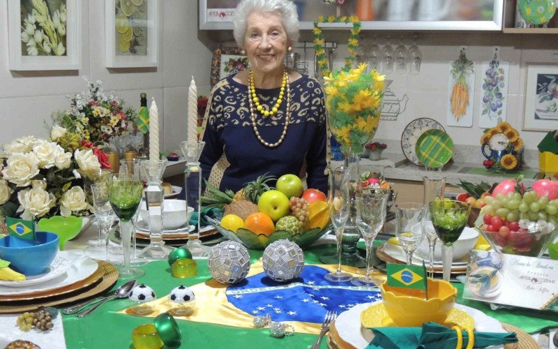 Dona Heda Seffrin ao lado de sua mesa decorativa para a Copa do Mundo | abc+