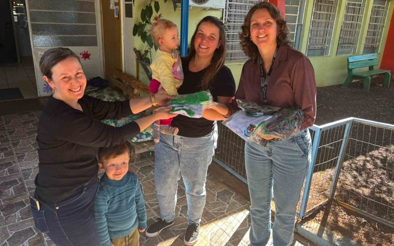 Denise (&agrave; esquerda) e J&eacute;ssica (no centro), recebem os uniformes da diretora Renata na Emei Est&acirc;ncia da Crian&ccedil;a